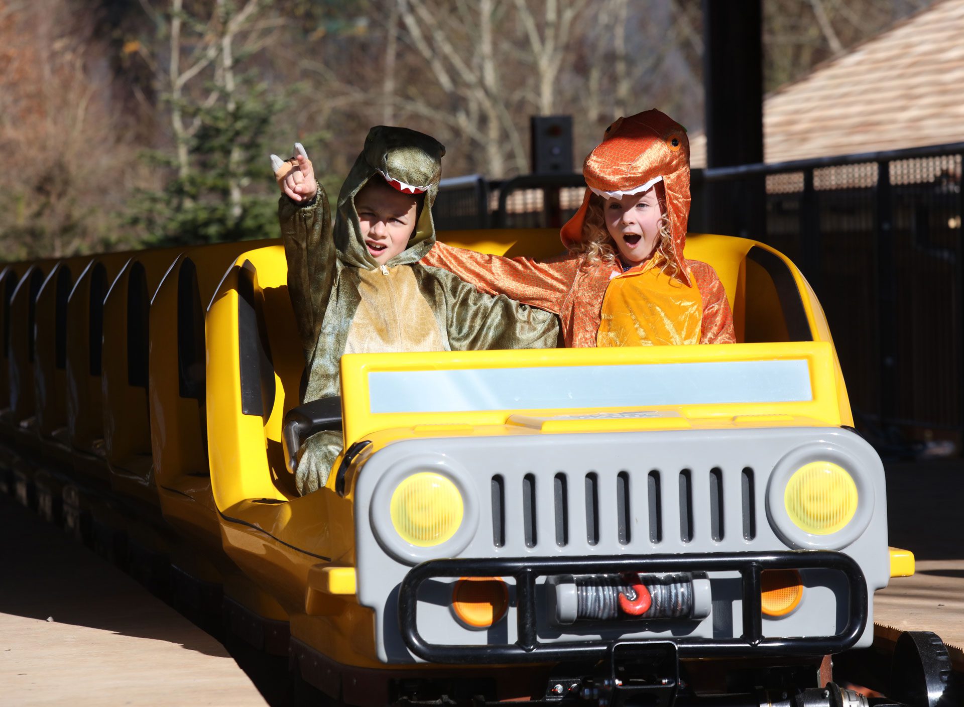 two kids in dinosaur costumes on a theme park ride
