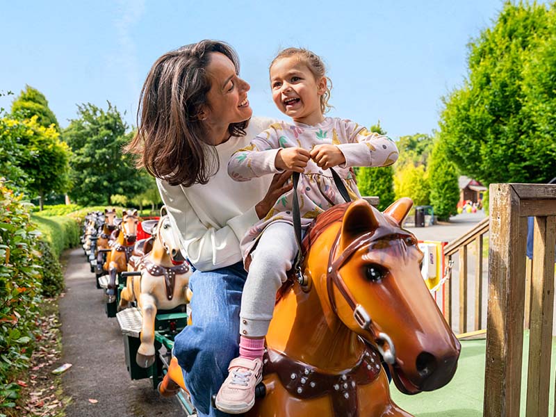 woman smiling at small girl on a theme park attraction