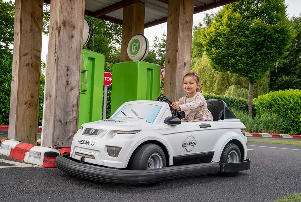 close up of a small girl smiling and driving a child sized car at emerald park