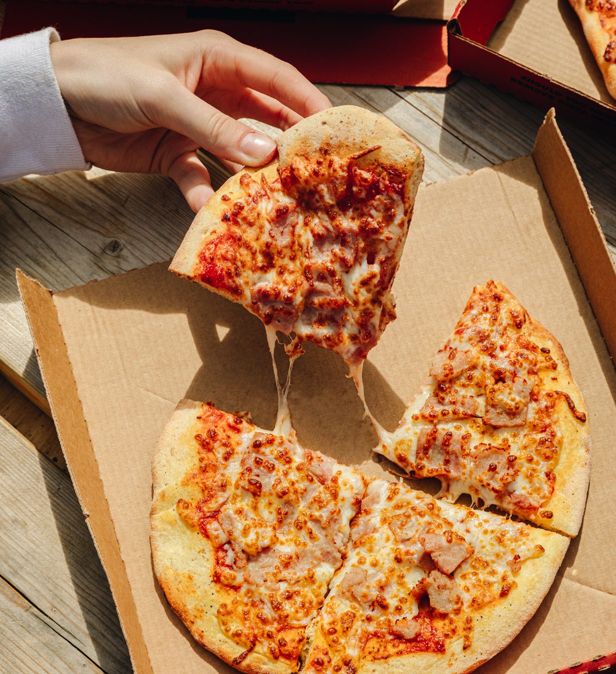 a small pizza slice being pulled by a hand