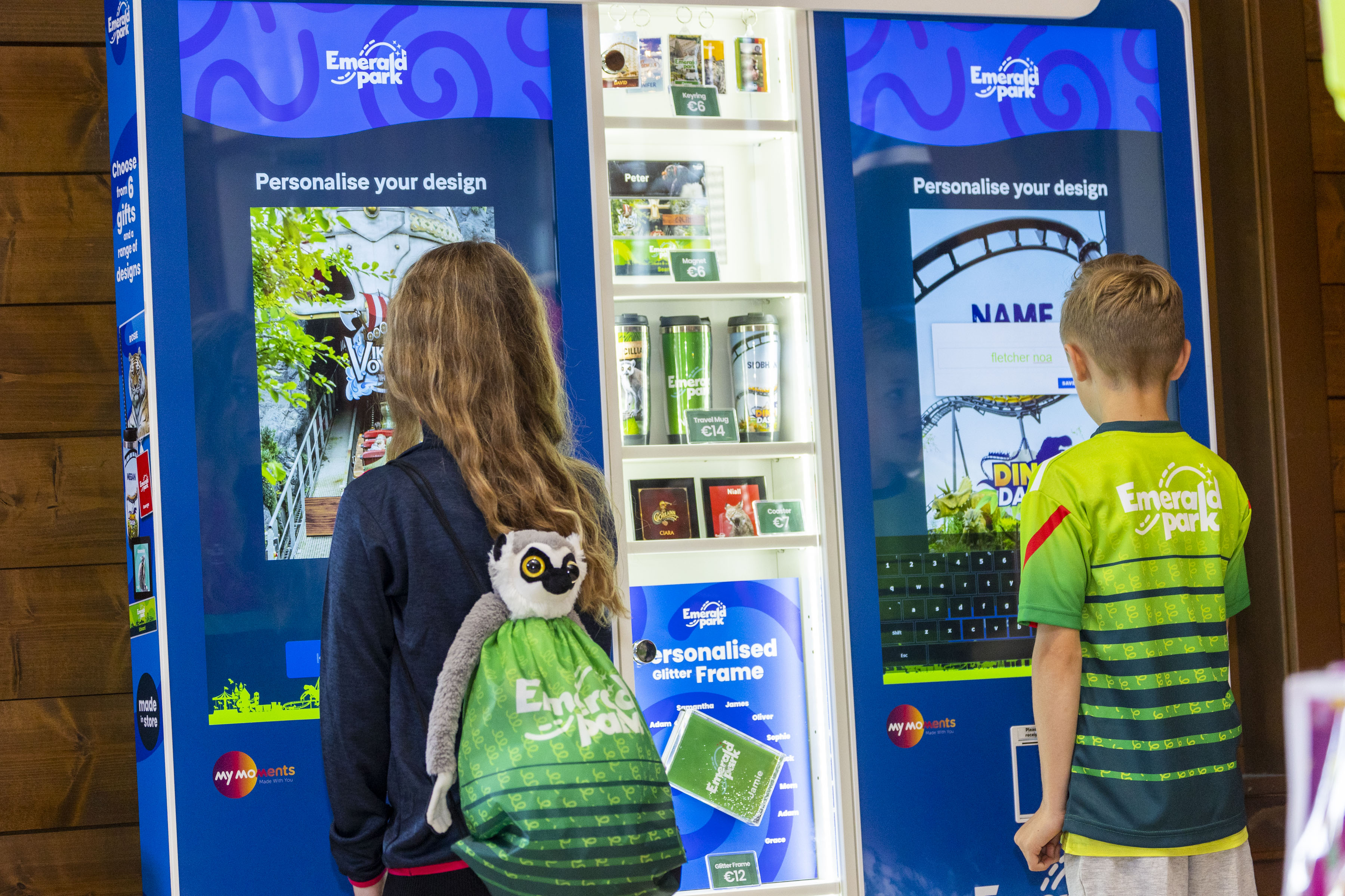 a boy and a girl at a My Moments machine in the Emerald Park gift shop