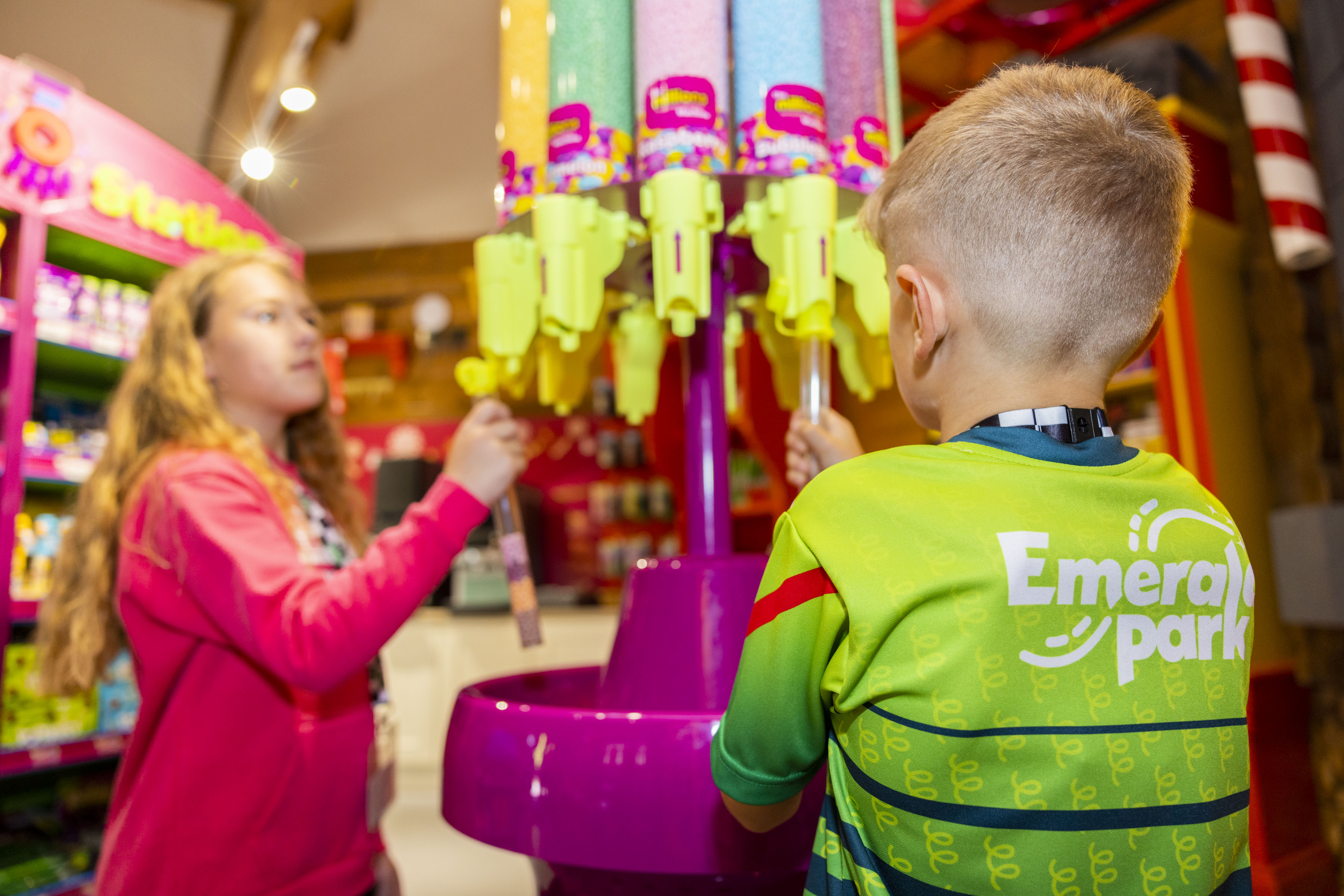 an image of a girl and boy filling up a tube full of colourful sweets