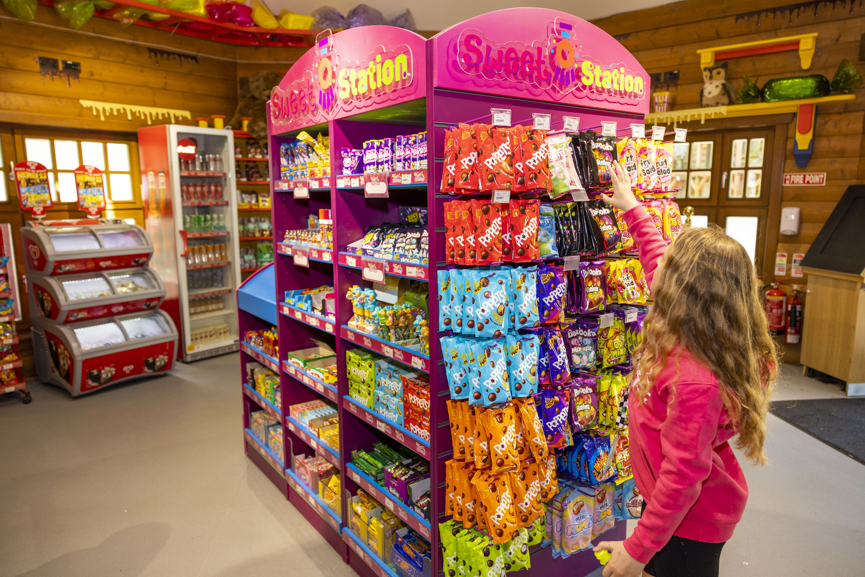 a sweet shop at Emerald Park filled with a variety of treats. A young girl is picking one pack off the shelves.