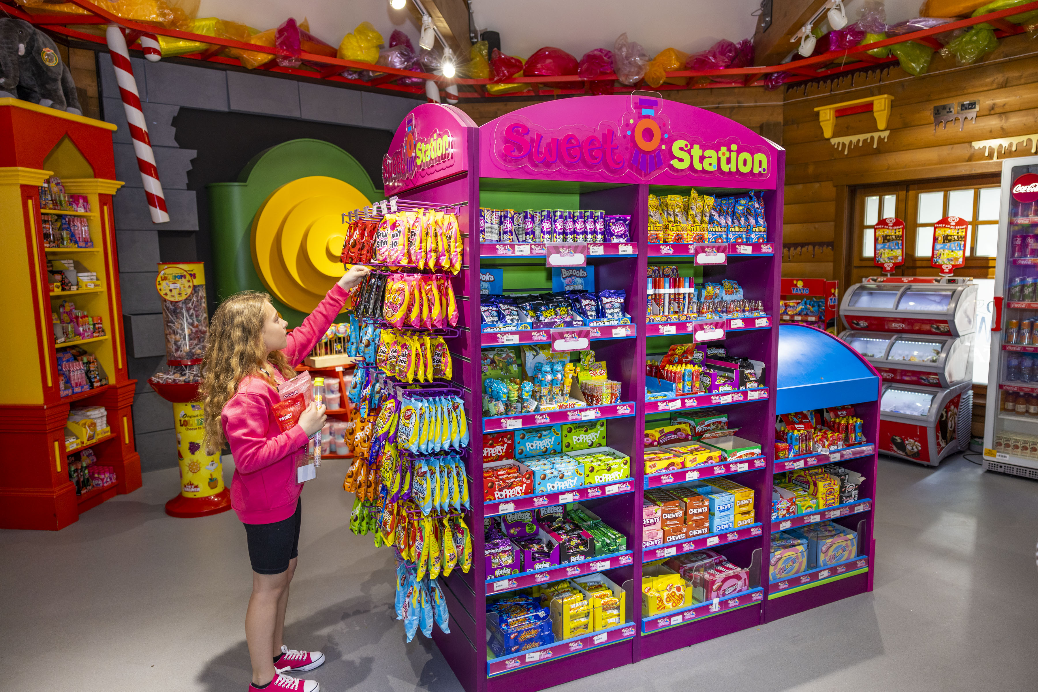 a sweet shop at Emerald Park filled with a variety of treats. A young girl is picking one pack off the shelves.