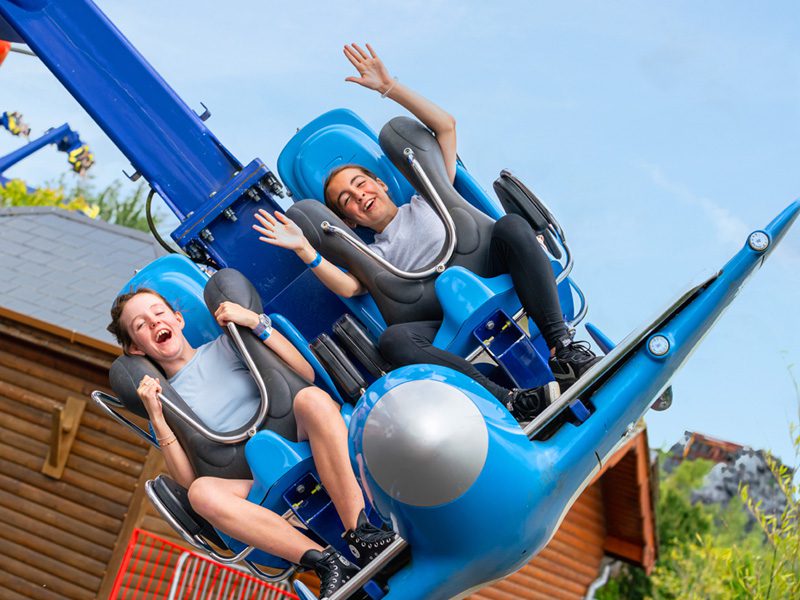 two girls waving and laughing on theme park ride