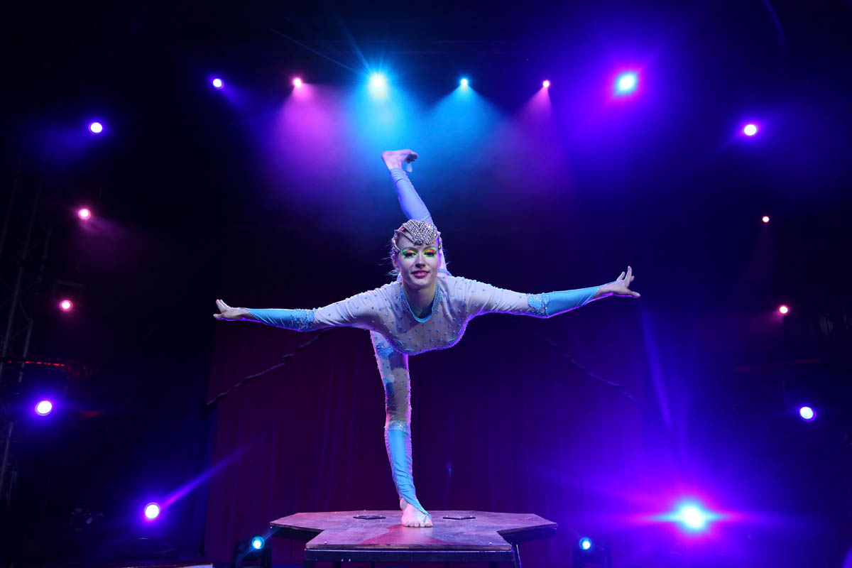 The acrobat performer on a platform standing on one leg doing an Arabesque move