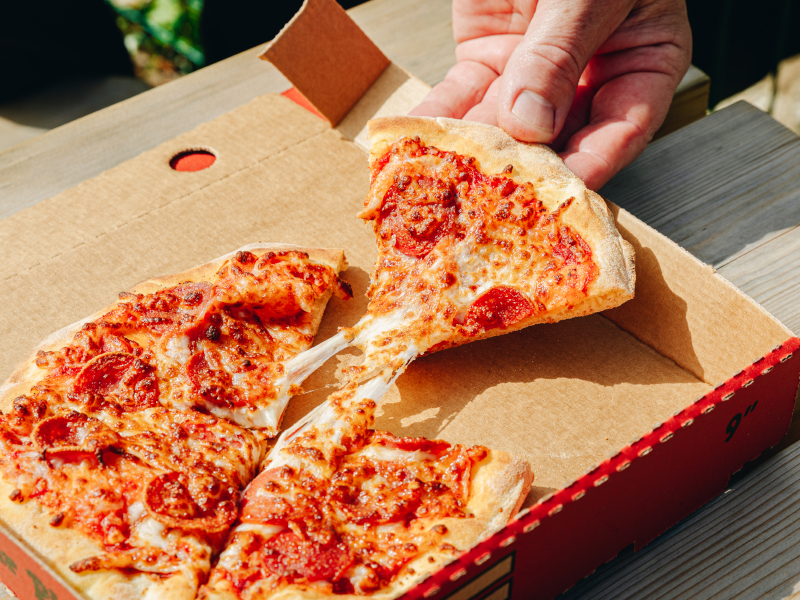 A close up of person taking a slice of pizza at Emerald Park