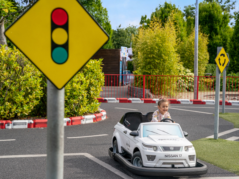 Young child driving the small size car around the driving school area.