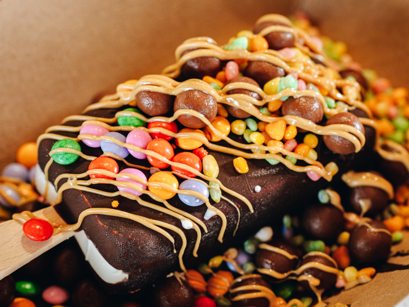 A close up of the chocolate ice cream toped with smarties and chocolate syrup