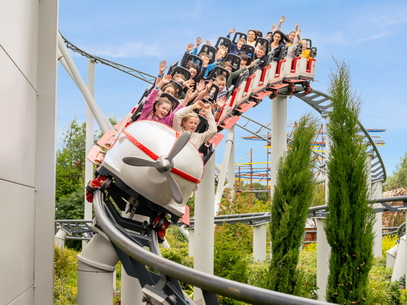 A group of children hands raised in the air while riding theme park ride
