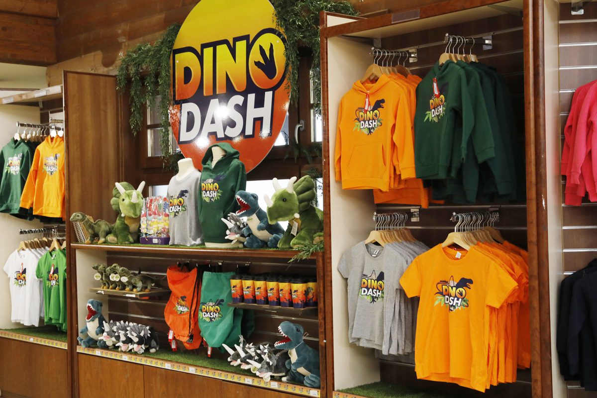 The wall of the emerald park gift store features merchandise for Dino Dash.