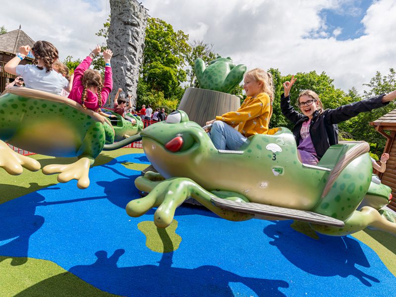 children waving and smiling on theme park ride at emerald park