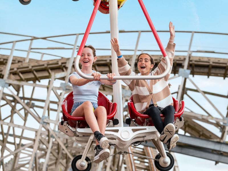 Two girls are having a good time while riding the Windstar at theme park.