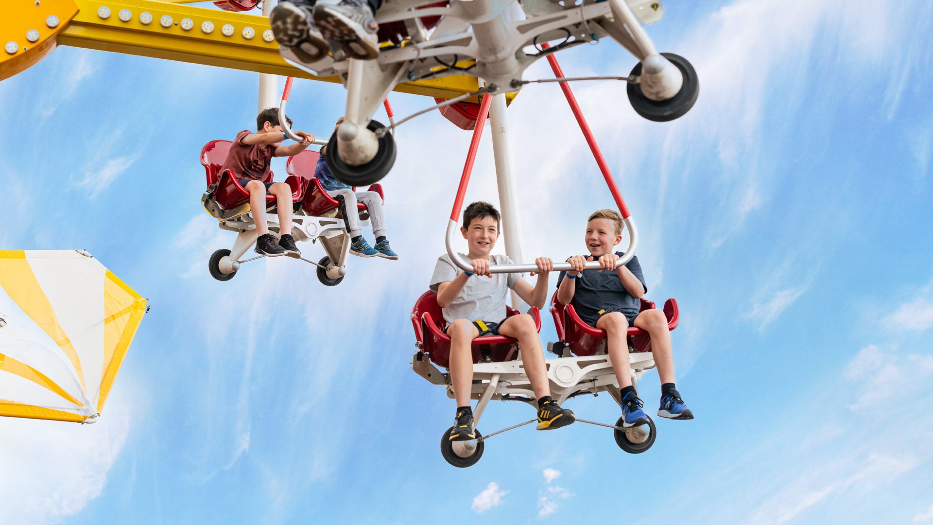 Children holding on tight on the Windstar ride in blue skies