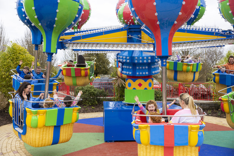 a group of children and adults enjoying a theme park attraction inspired by a hot air balloon