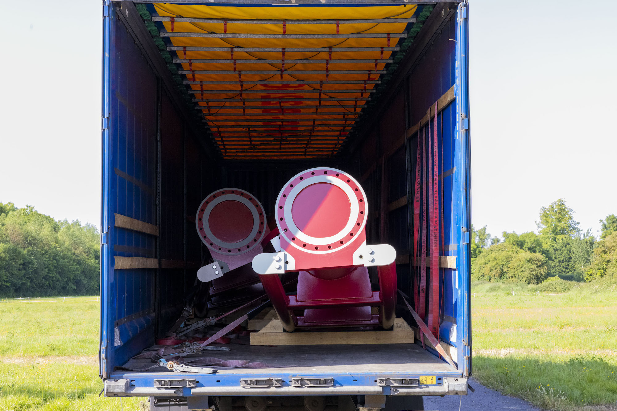 red rollercoaster track being unloaded from a truck