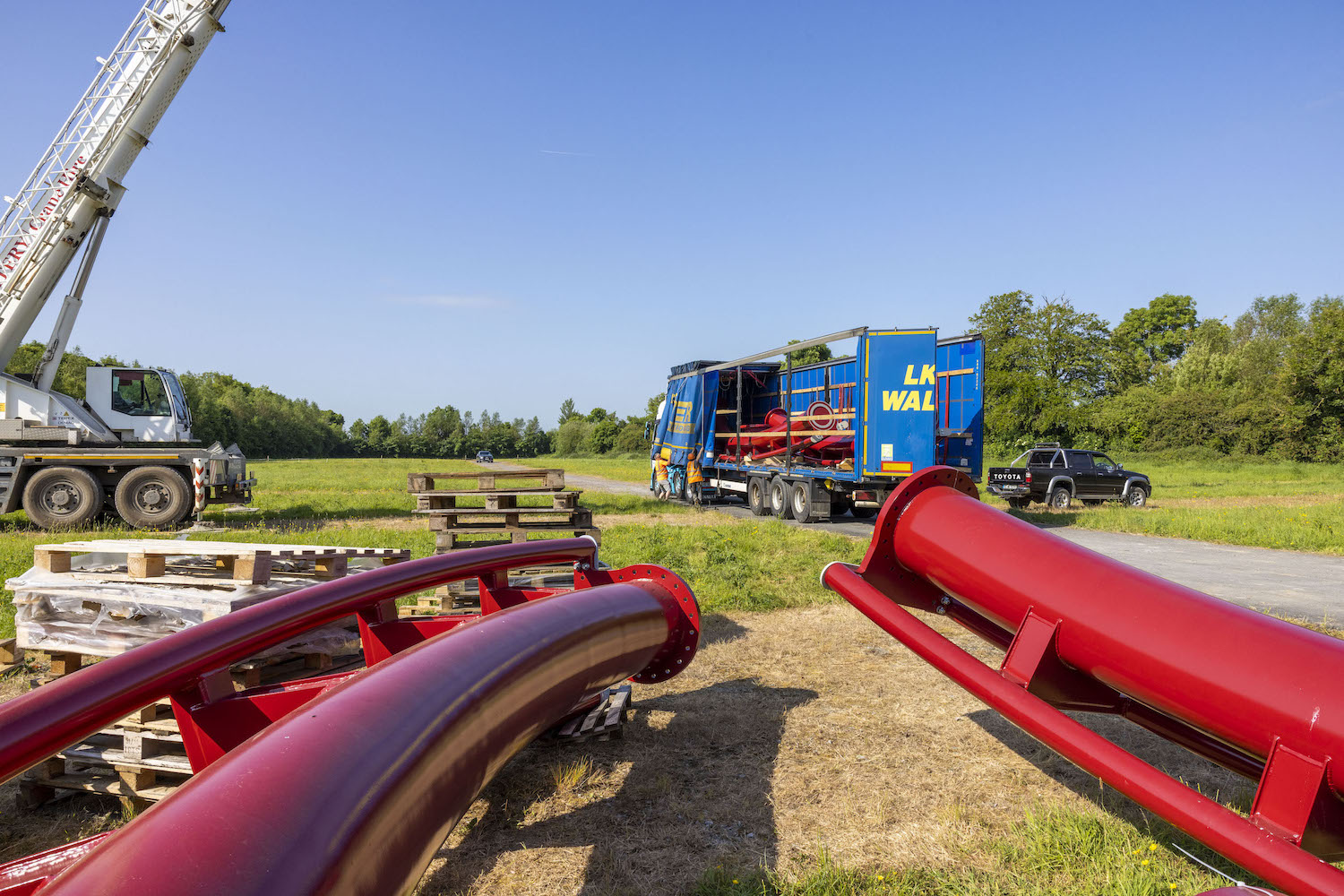 red rollercoaster track being unloaded from a truck