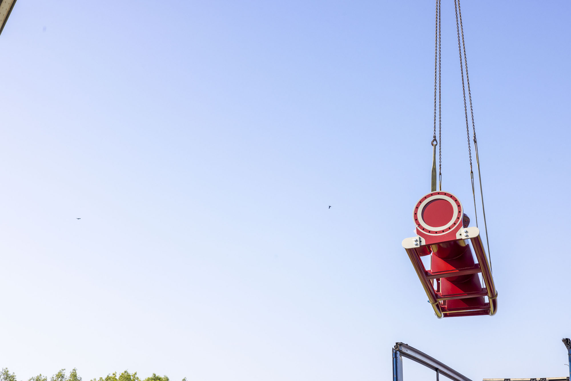 a red rollercoaster track being lifted from a truck