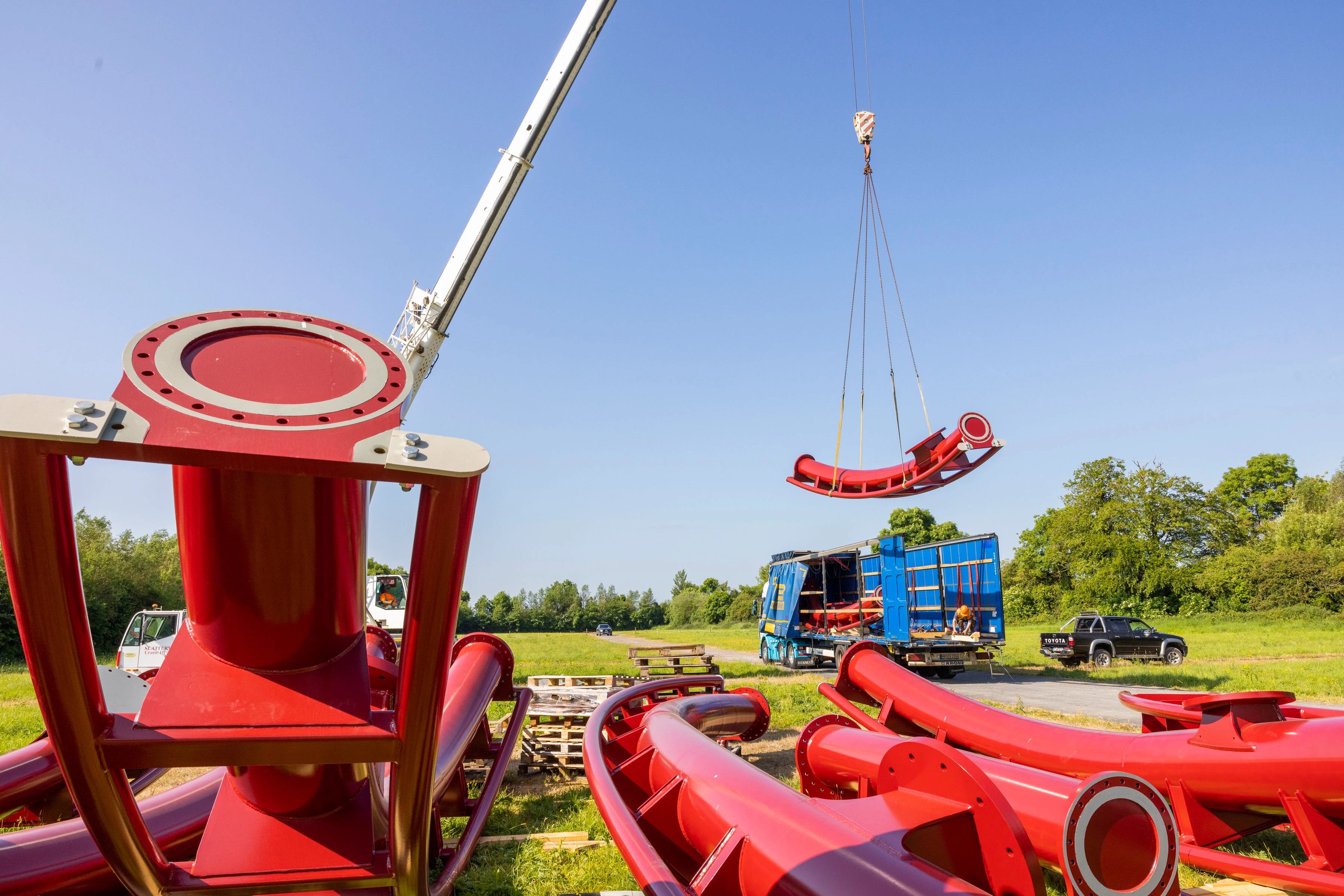 a rollercoaster track delivery of a red track. One piece is being lifted from a truck