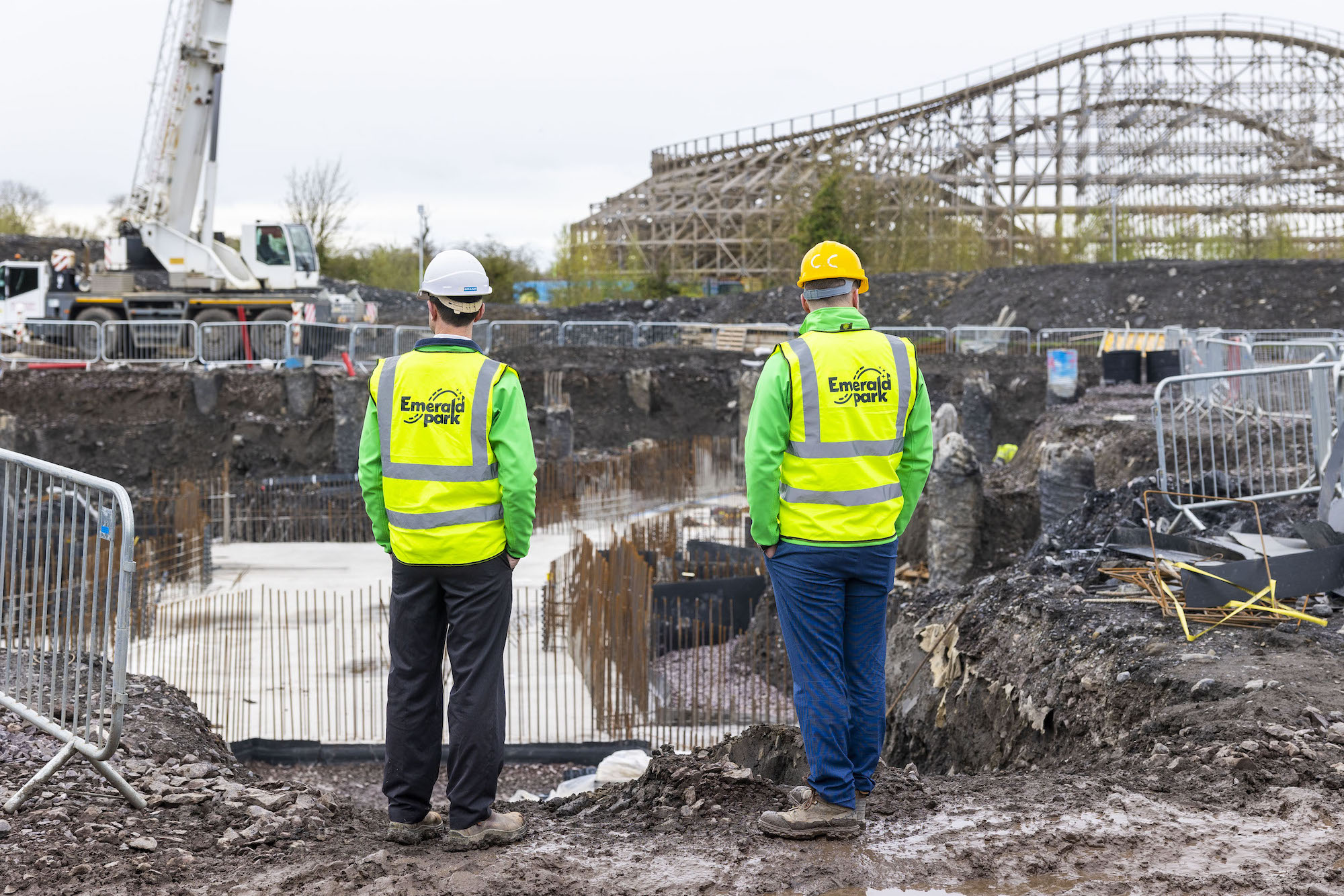 a construction site with two men and a rollercoaster in the back