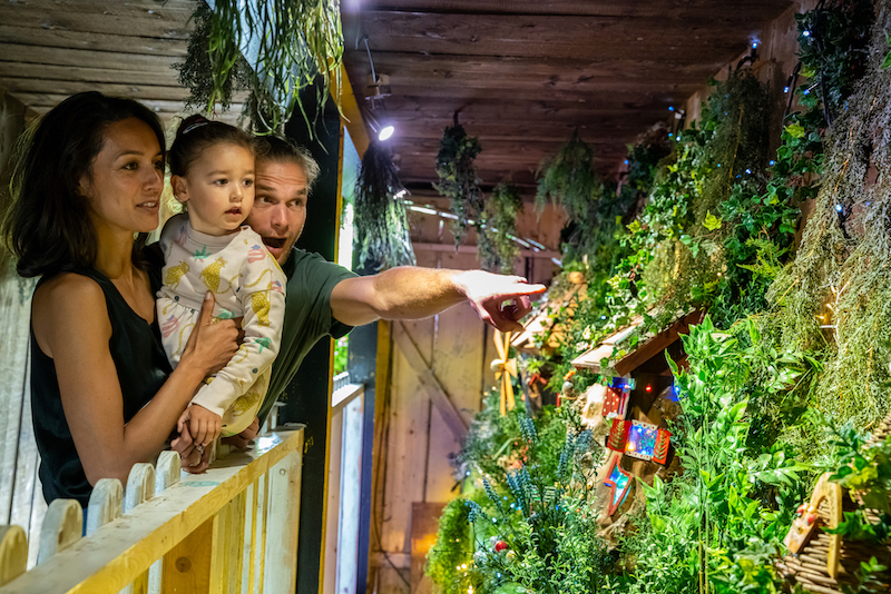 parents holding their child point at a fairy house