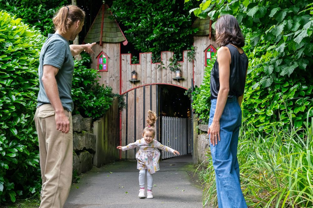 a child jumping while her parents look at her smiling