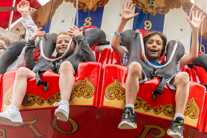 children in shorts waving from theme park ride at emerald park