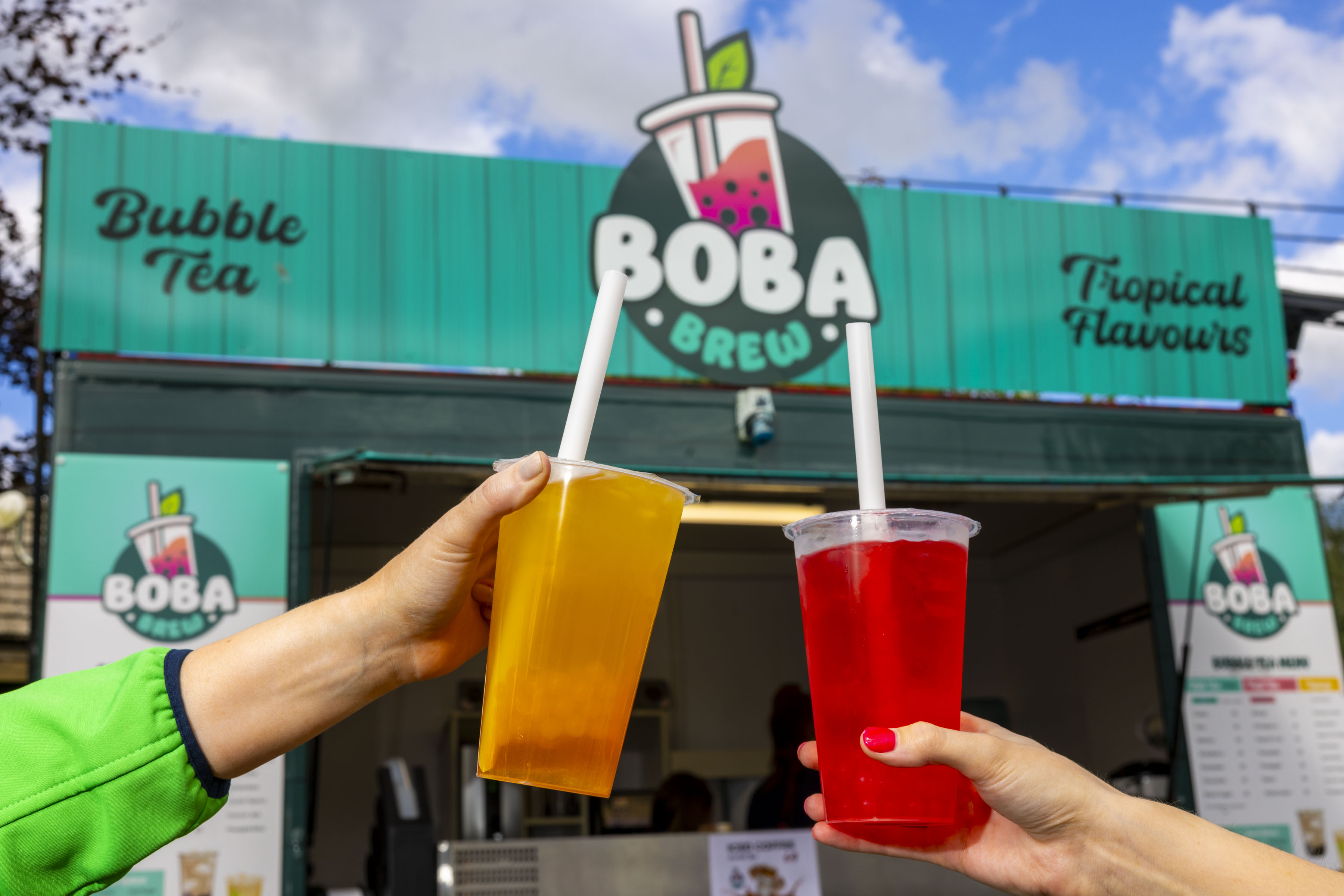 a red and yellow bubble tea outside a bubble tea unit called Boba Brew
