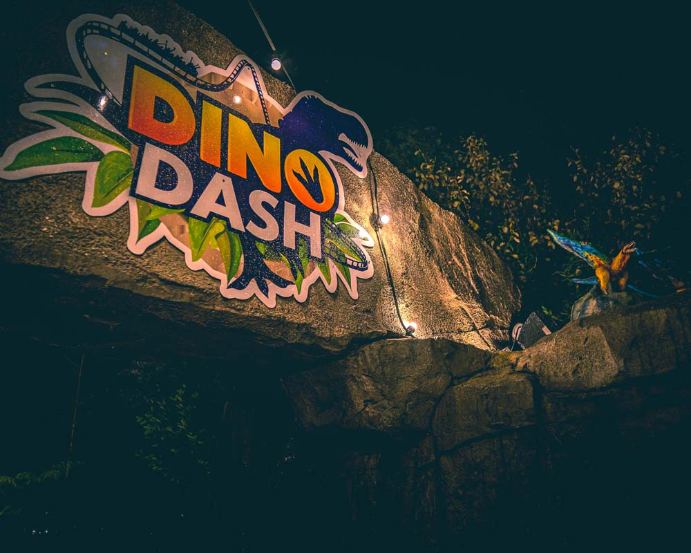 the entrance to the Dino Dash attraction at Emerald Park. The entrance has the ride logo and lights around it.