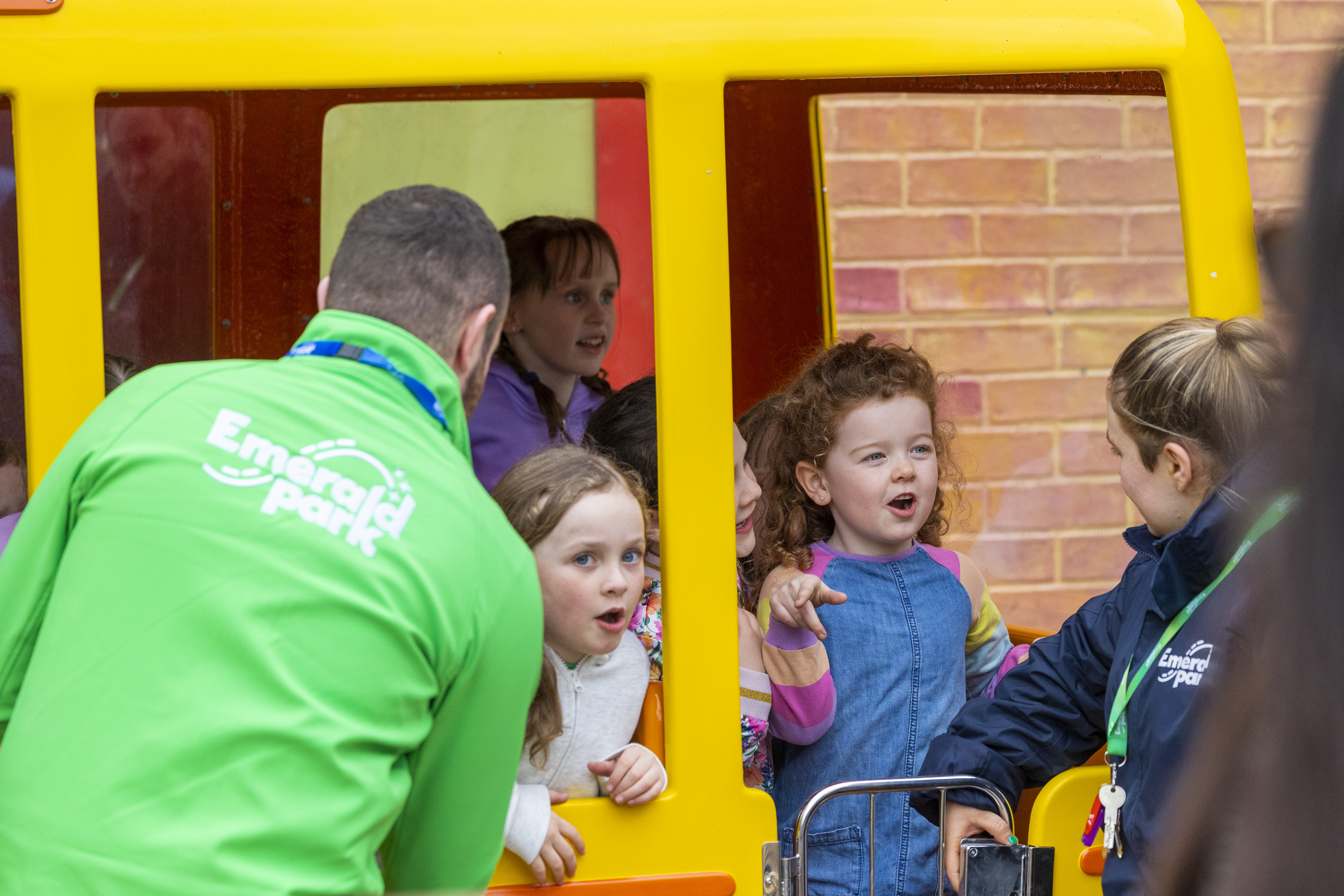 two Emerald Park staff members at a ride in Emerald Park chatting to a child